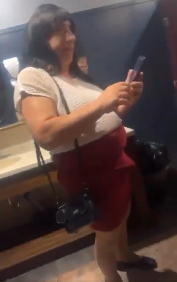 Una mujer transgénero con una prominente tienda de campaña espera en la fila del baño de mujeres en Burlington, Massachusetts.