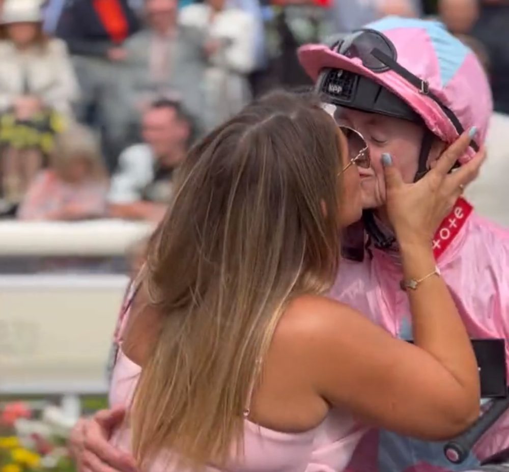 El jockey ganador del Ebor Festival, Sean Kirrane, recibe un beso de Jolene, la propietaria de Live In The Dream.