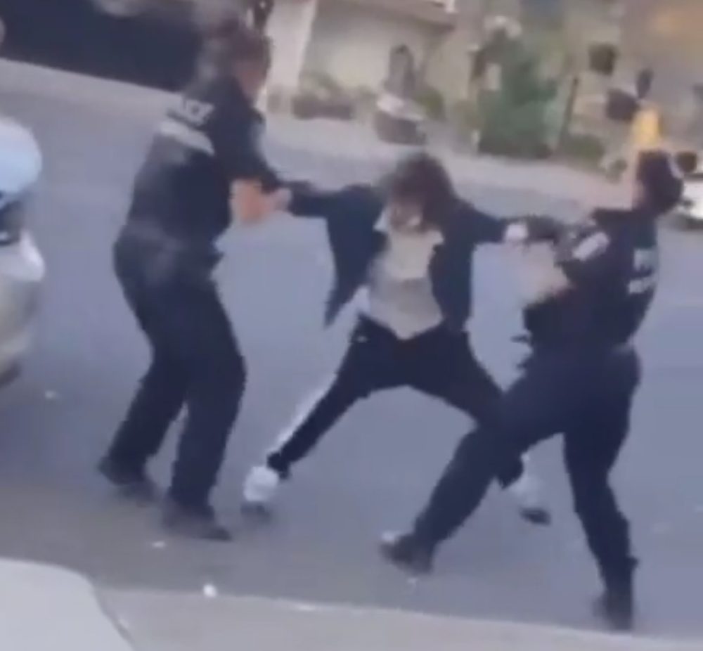 Dos mujeres poIicía intentan reducir a un hombre.