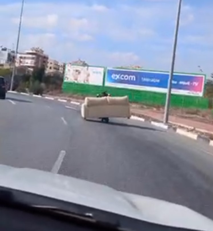 Avistan en Elche a un individuo llevando un sofá con un patinete eléctrico.