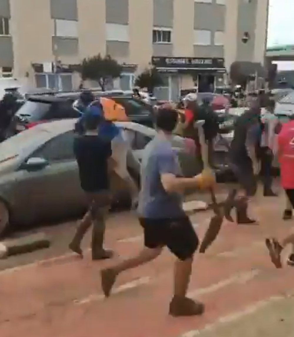 Momento en el que Pedro Sánchez huye en un coche oficial mientras la gente le persigue con palas y escobas en las manos.