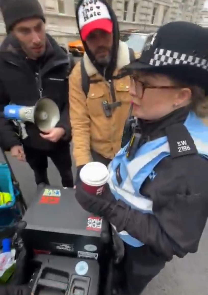 Una policía británica invita a unos manifestantes a retirar una pegatina en la que pone “FCK HMS” (F*ck Hamás).