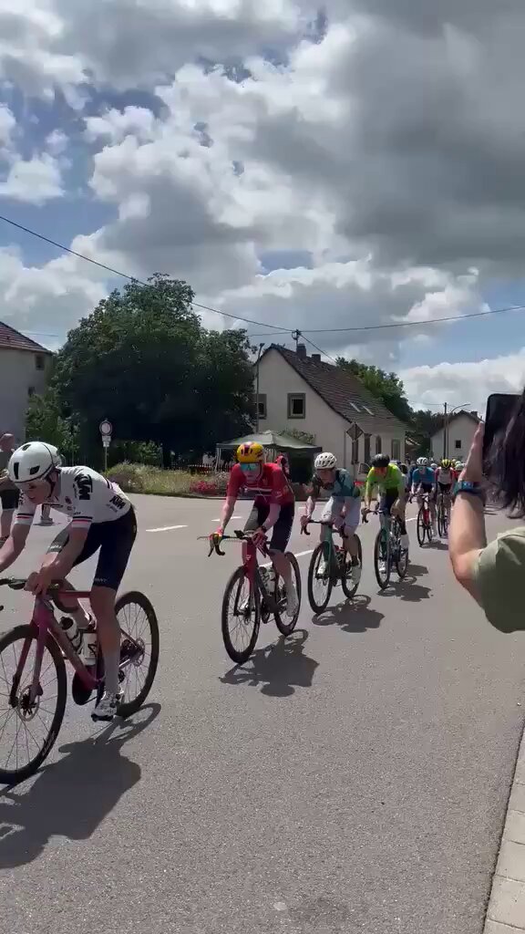 Un señor en silla de ruedas intenta cruzar la carretera mientras pasaba el pelotón de una etapa ciclista (Saarland Trofeo).