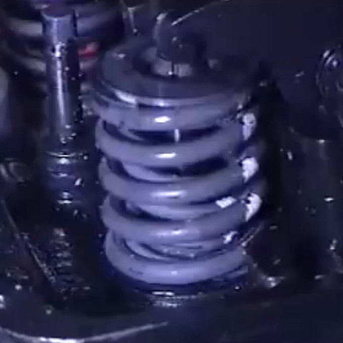 A 8.500 RPM, este muelle de válvula opera a ~70 Hz. El efecto estroboscópico de la cámara crea la ilusión de cámara lenta, pero revela en tiempo real el fenómeno de rotación axial del muelle, esencial para uniformizar el desgaste térmico y mecánico en el asiento de la válvula.