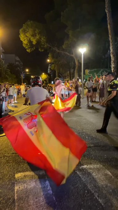 Un policía torea a un motorista usando una bandera de España durante las celebraciones del mundial.