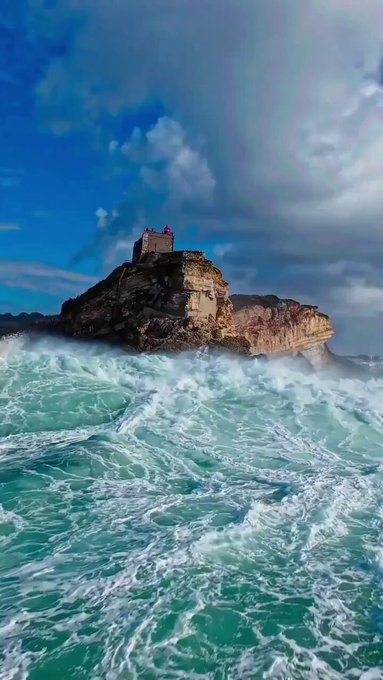 Una ola tapa por completo un acantilado en Nazaré, Portugal.