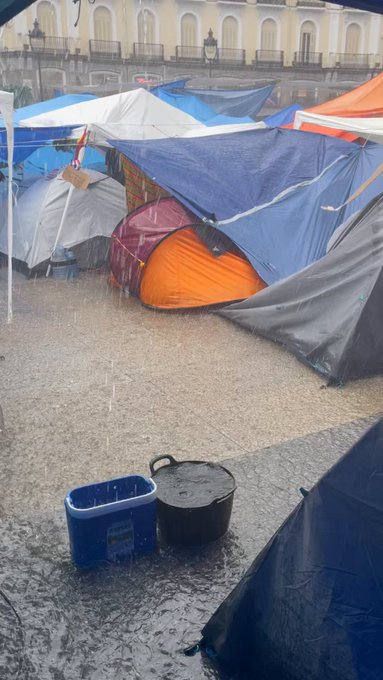Caos logístico en la acampada: las lluvias azotan la Micrópolis de Puerta Del Sol con enormes inundaciones, ruidos atronadores y falta de respuesta protocolaria.
