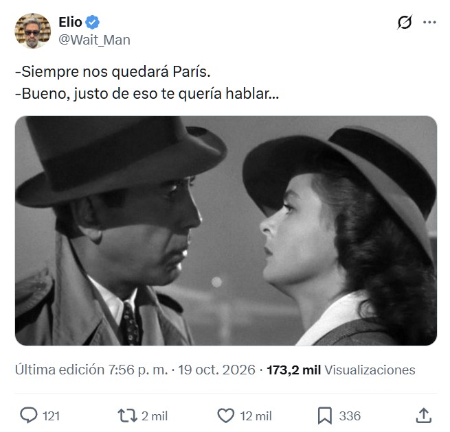 Pareja disfrutando de una bebida en la terraza de un café cerca del Arco de Triunfo mientras arden las calles de París.